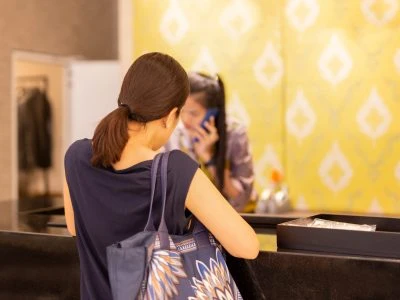 Woman at checkout in clothing store with staff on the phone enquiry